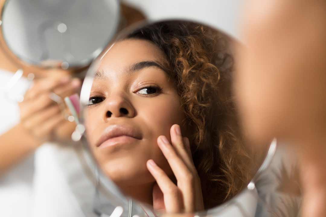 Woman looking in the mirror at her skin