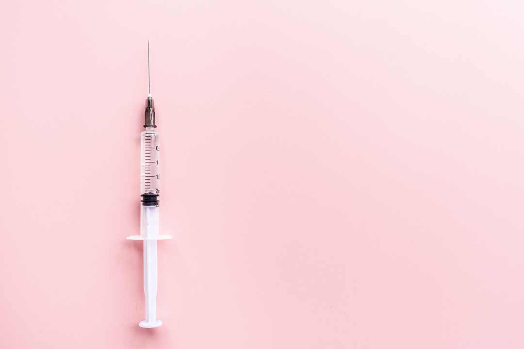 Medical syringe on a pale pink background