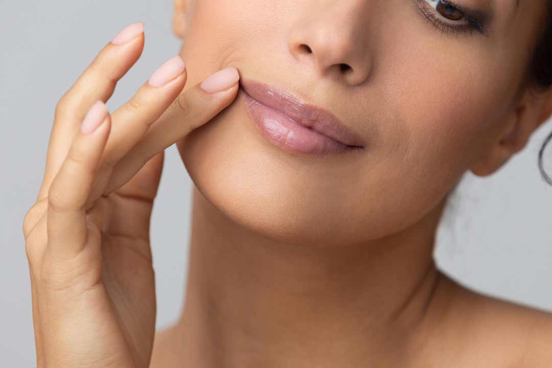 Woman touches corner of lip, with a slight smile